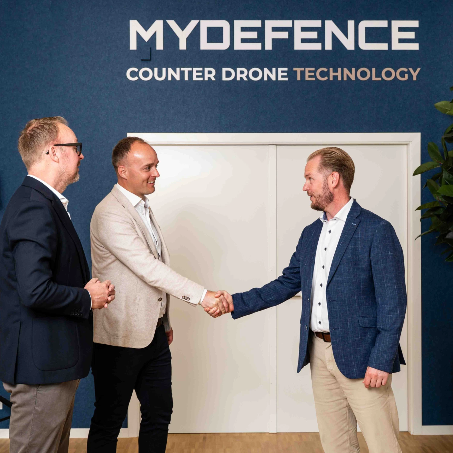 Nordic Marine Capital giver håndtryk til MyDefence Counter Drone Technology foran firmaets logo.